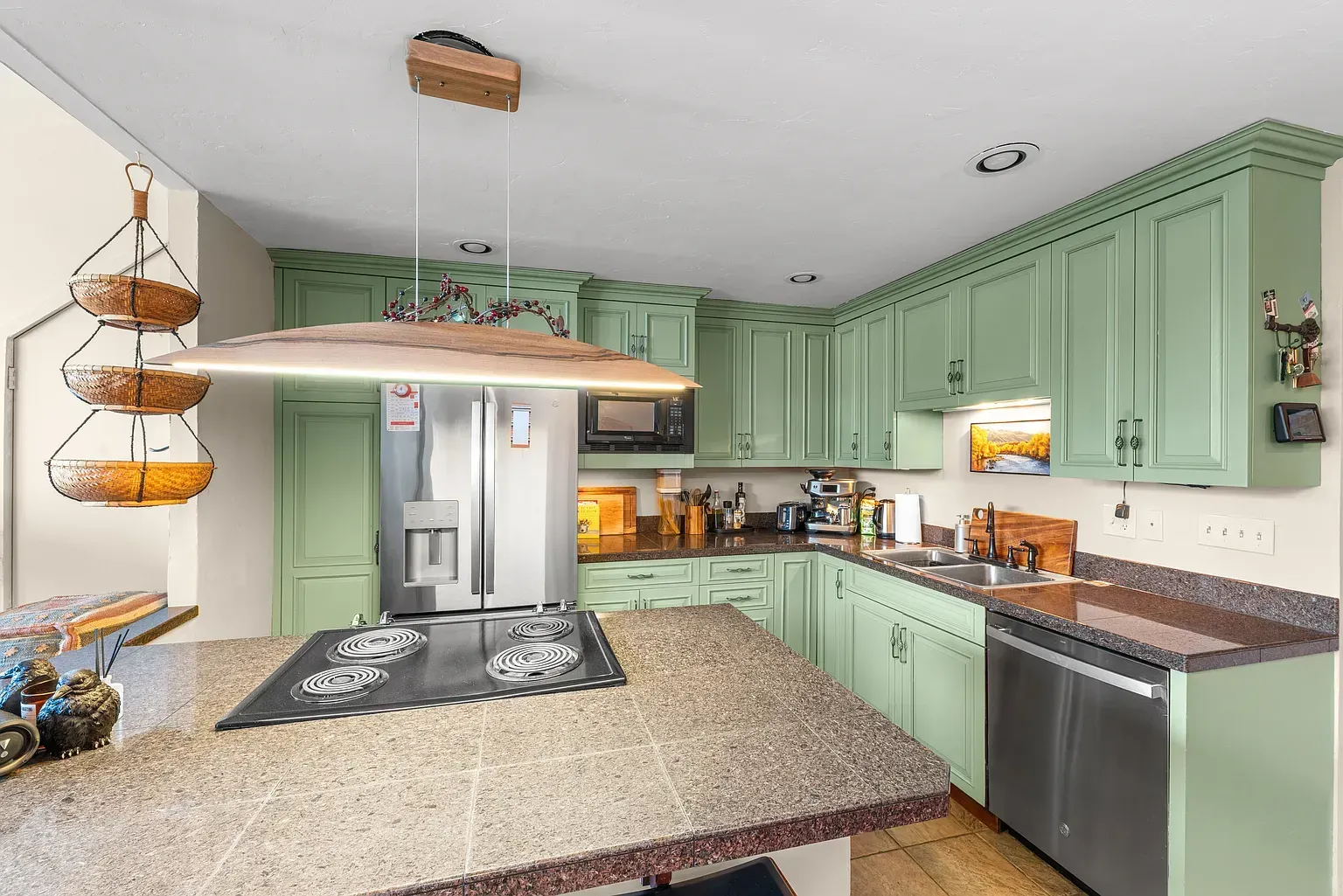 Bright kitchen with mint cabinets, granite island, stainless steel appliances, and wood floor