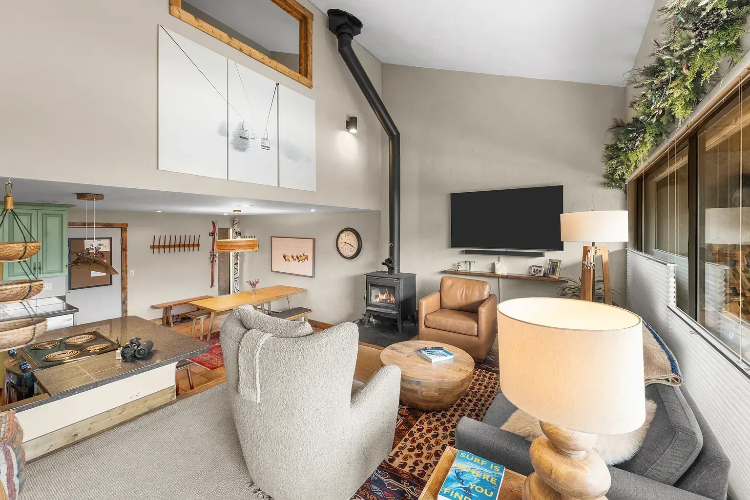 Cozy living room with beige chairs, fireplace, wall-mounted TV, and large window seating area