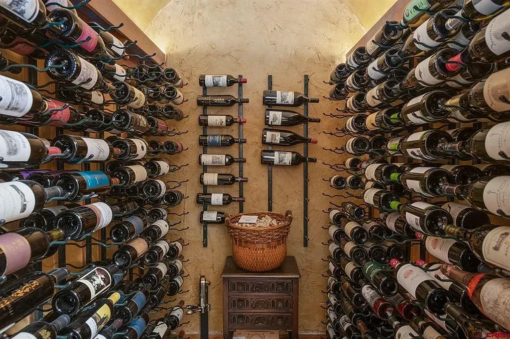 Wine cellar with rows of bottles on both walls and a central storage rack in a narrow room