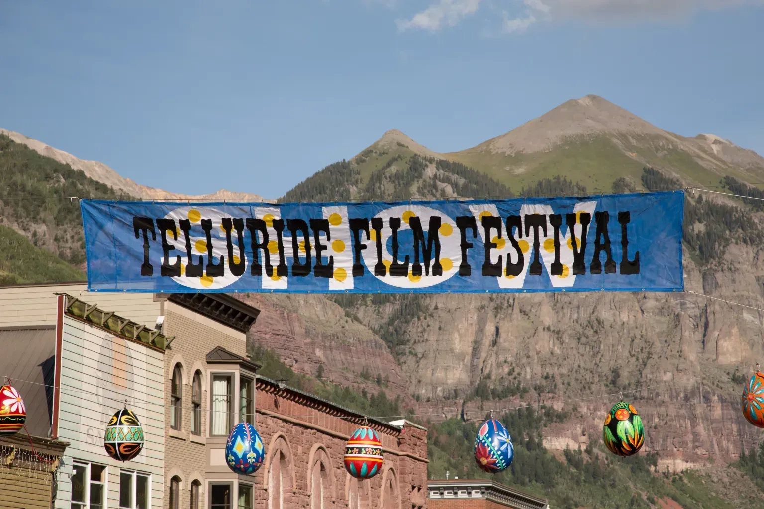 Telluride Film Festival banner over mountain town street with blue sky and tan peaks