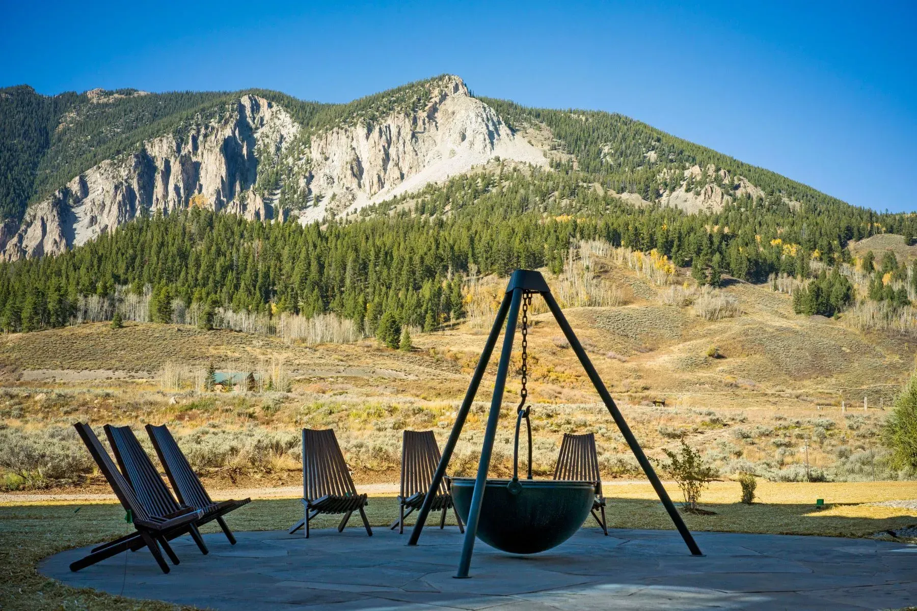 Campfire seating by a lake with mountains and pine forest in the background