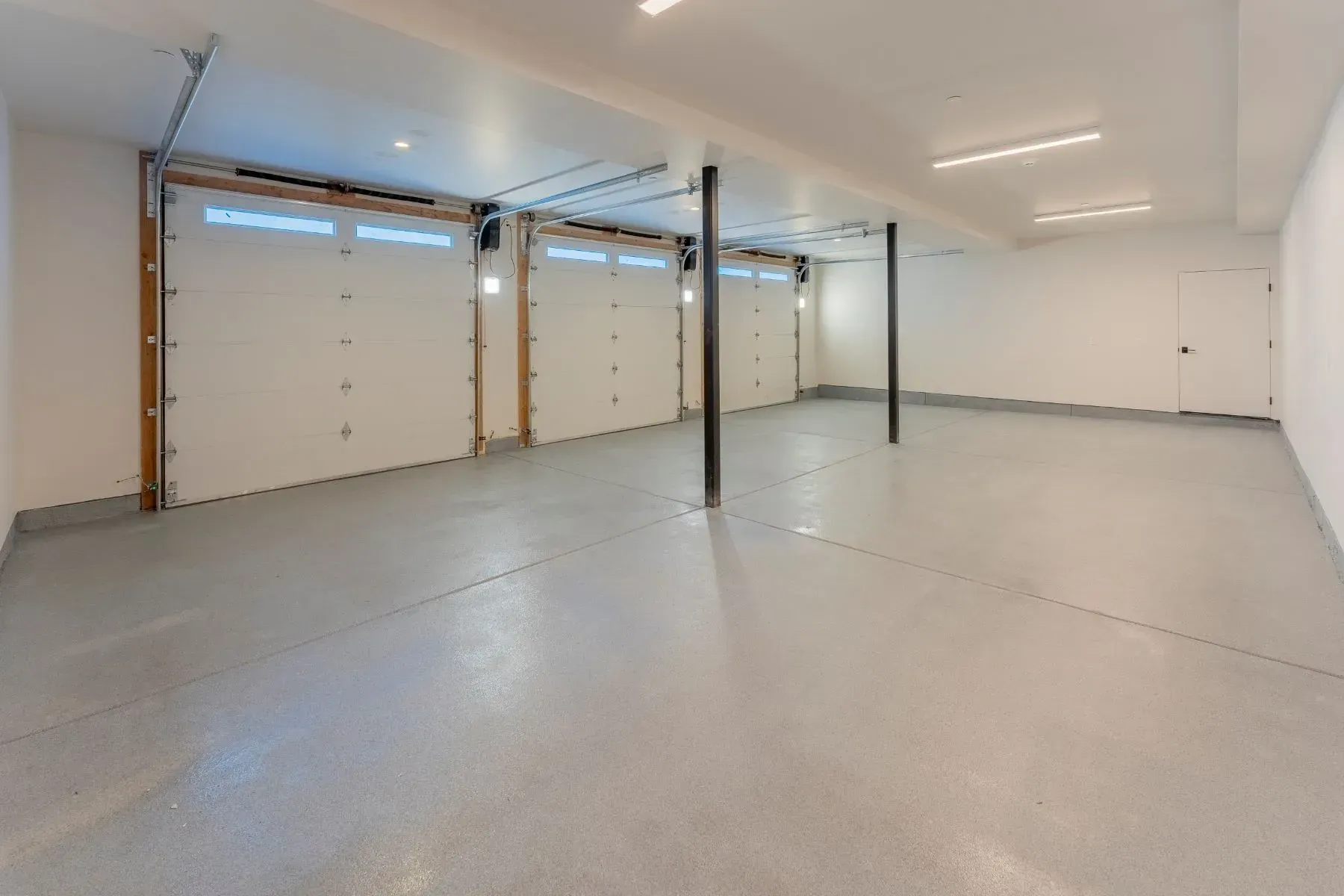 Empty white garage with polished concrete floor and metal support posts