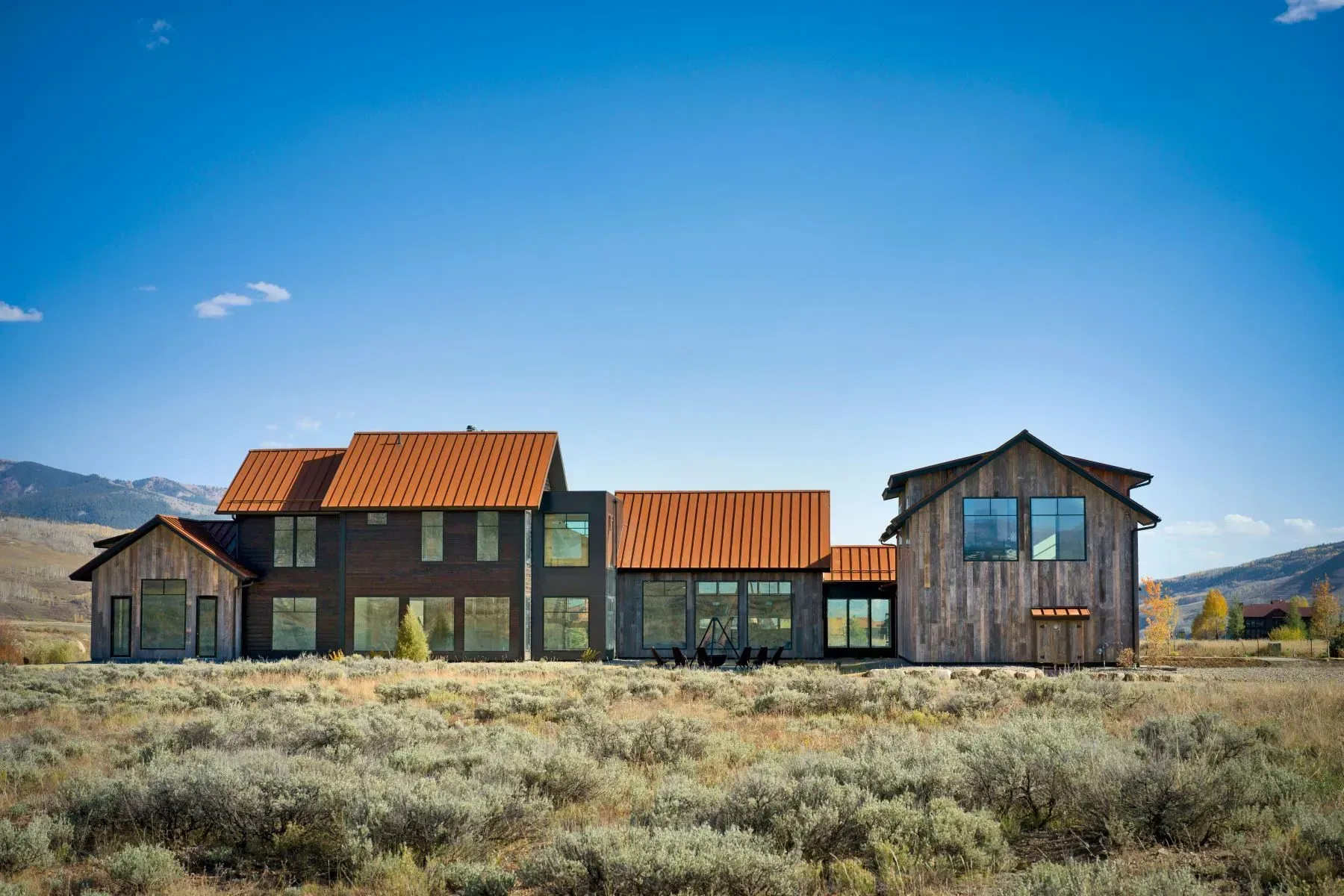 Rustic wooden houses with red roofs in a dry field under a clear blue sky