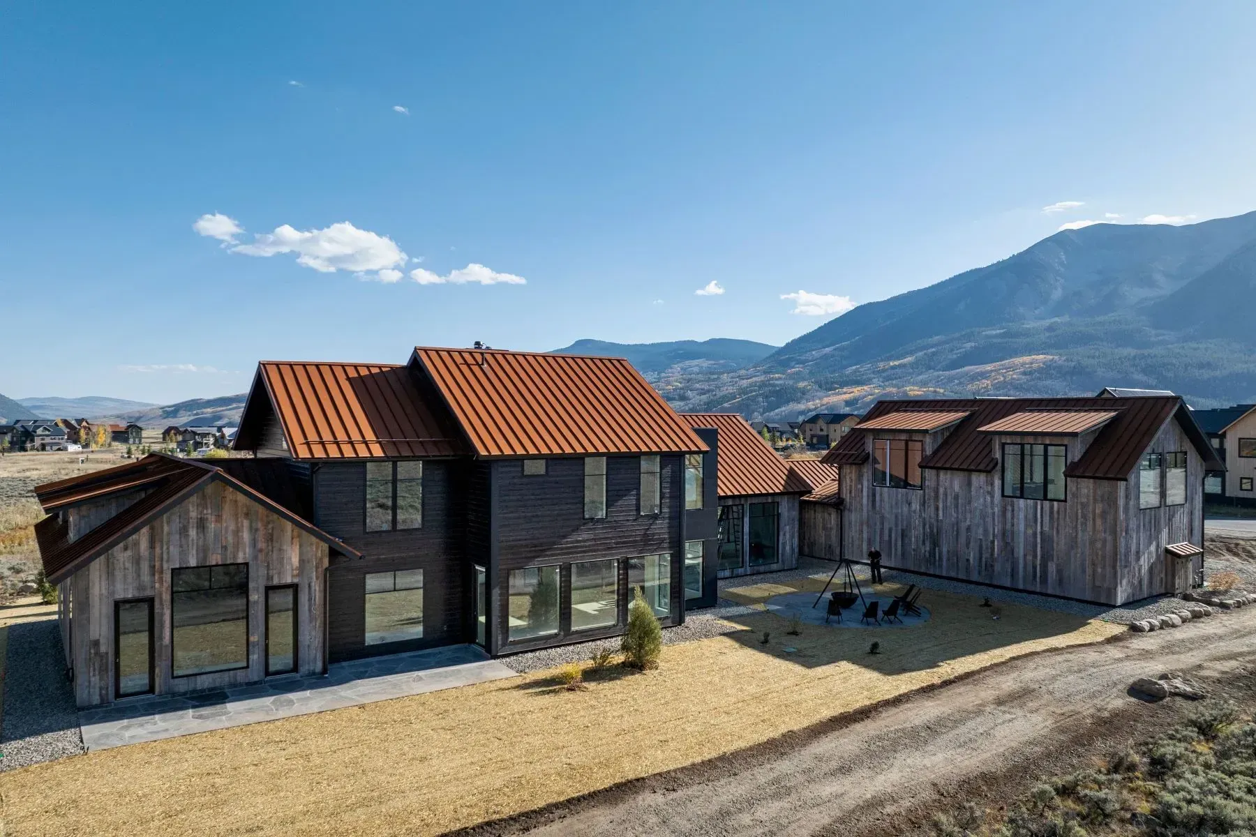 Wooden houses with red roofs on a hillside under a clear blue sky, with mountains in the background