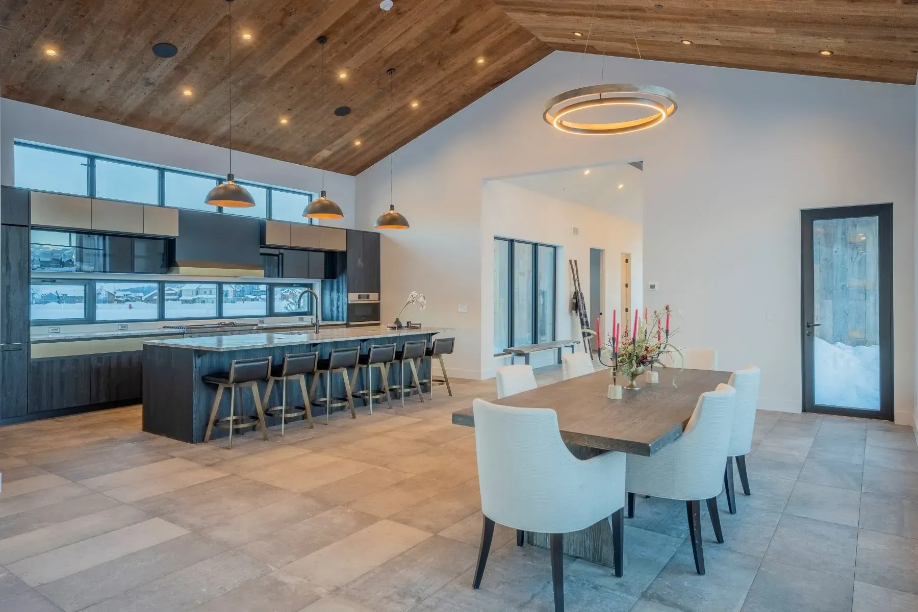 Modern open-concept kitchen and dining area with wood ceiling, large island, and white dining chairs