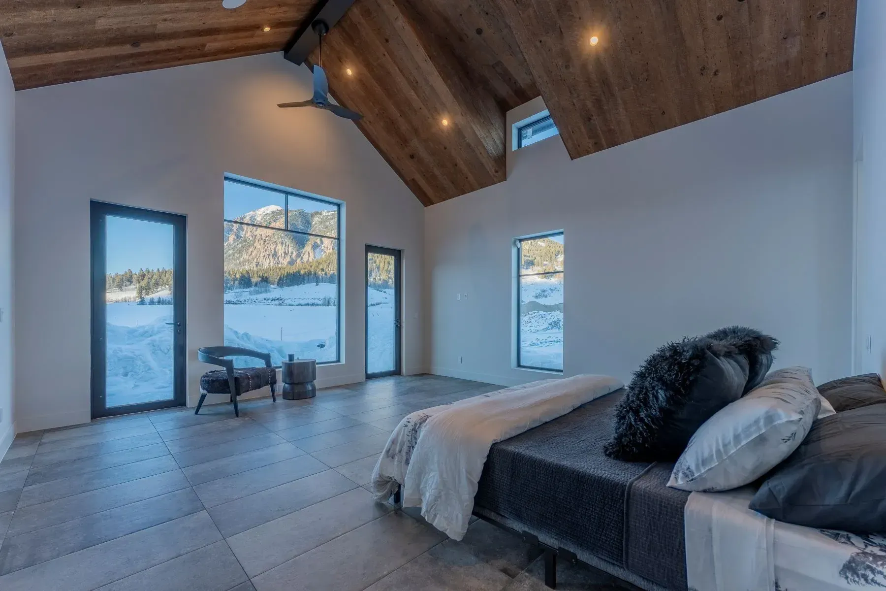 Modern bedroom with vaulted wood ceiling, large windows, and lake or mountain view