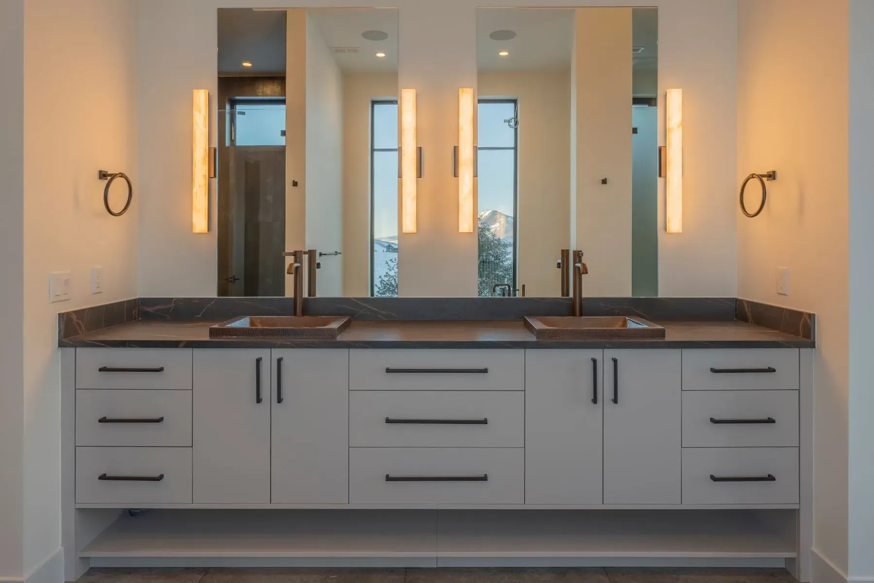 Modern bathroom vanity with double sinks, large mirrors, and wall sconces