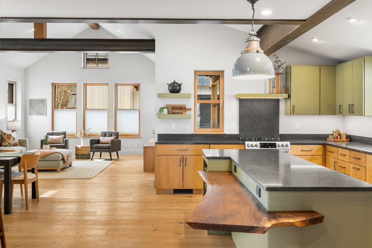 Bright modern kitchen and dining area with wood floors, island, pendant light, and large windows
