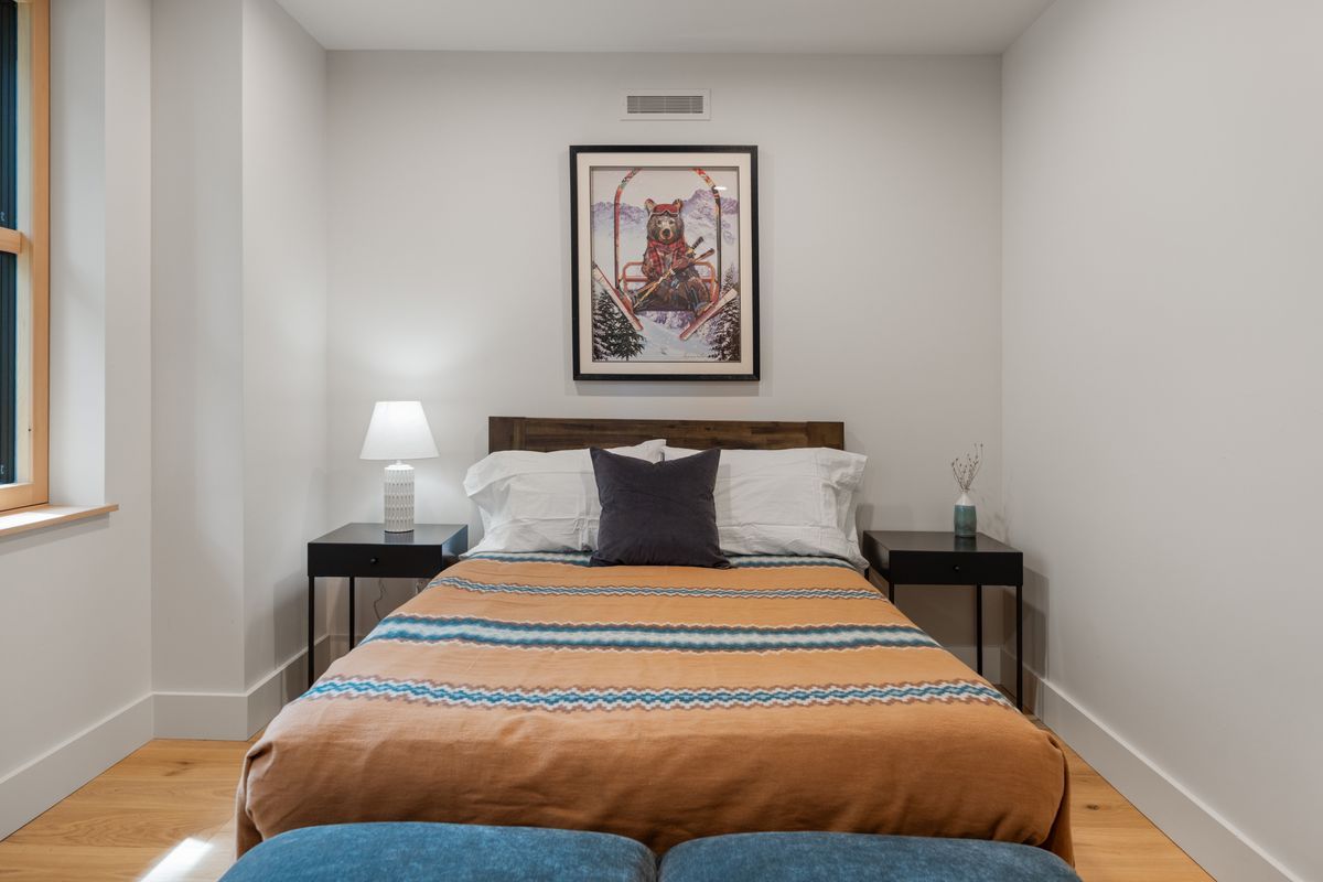 Small bedroom with a neatly made bed, bedside lamps, and a framed picture above the headboard.