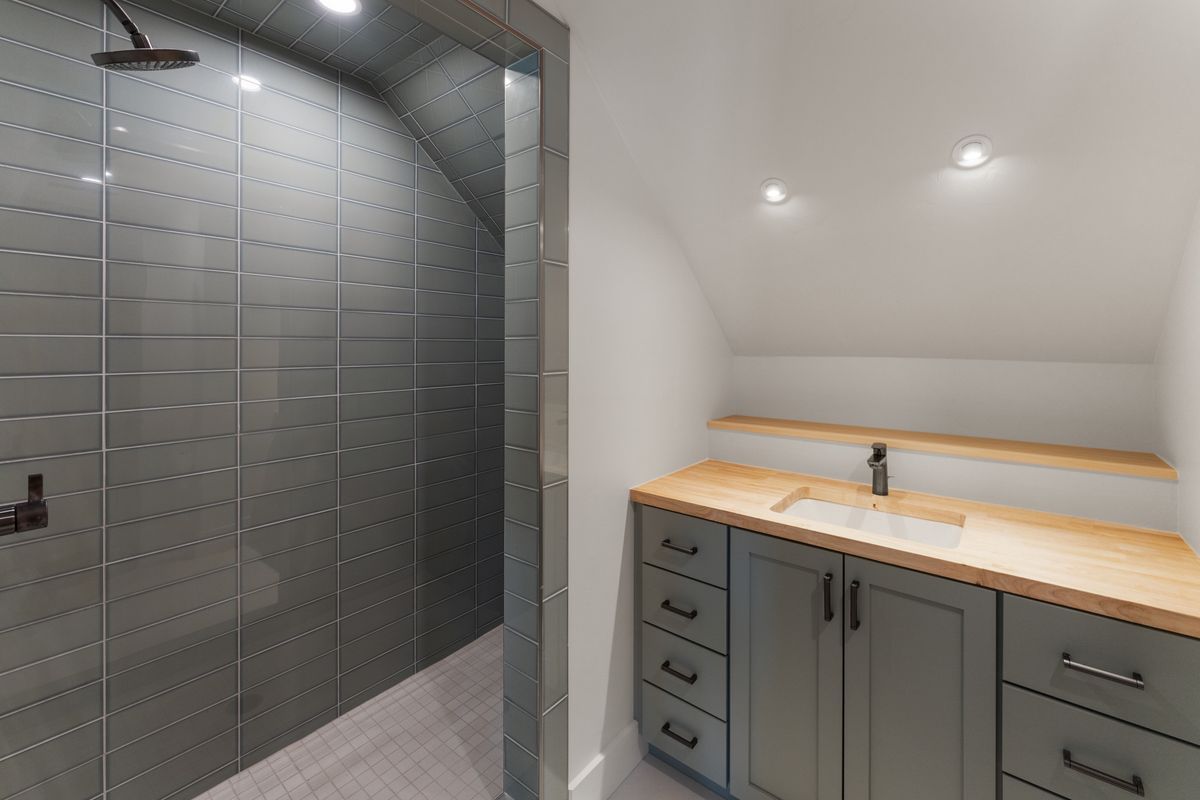 Modern bathroom with glass shower enclosure, vanity, and lit countertop mirror area