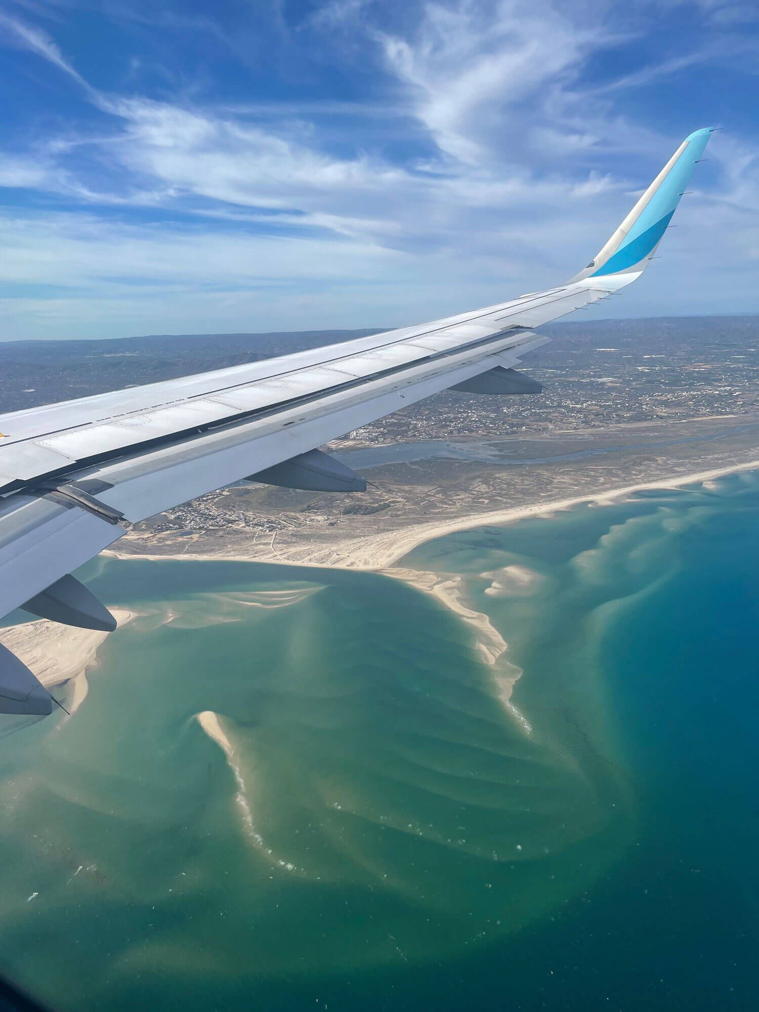 Algarve: Ein Flugzeug fliegt über eine Küstenlinie.