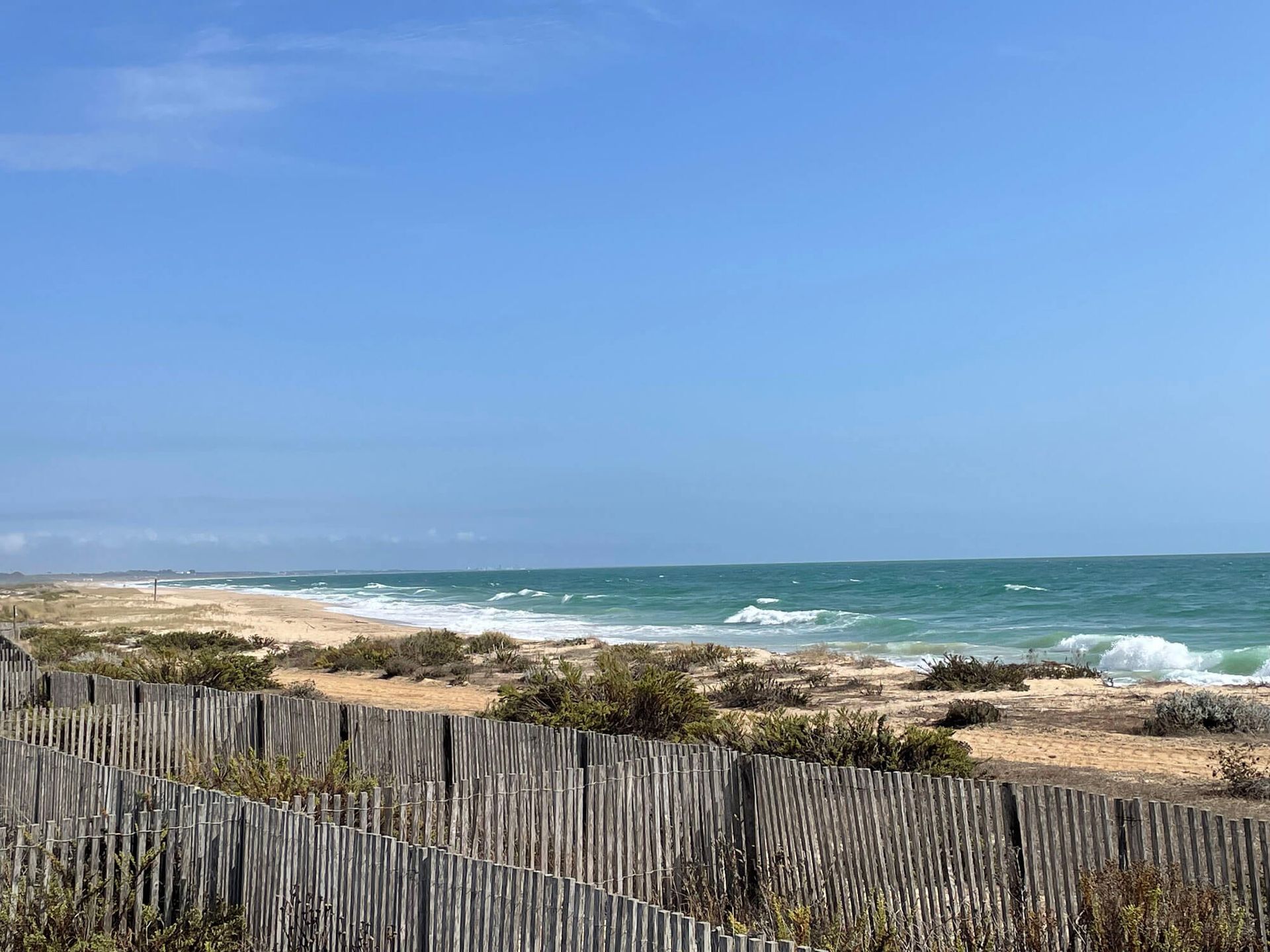 Ein Holzzaun umgibt einen Strand mit Blick auf das Meer an der Algarve