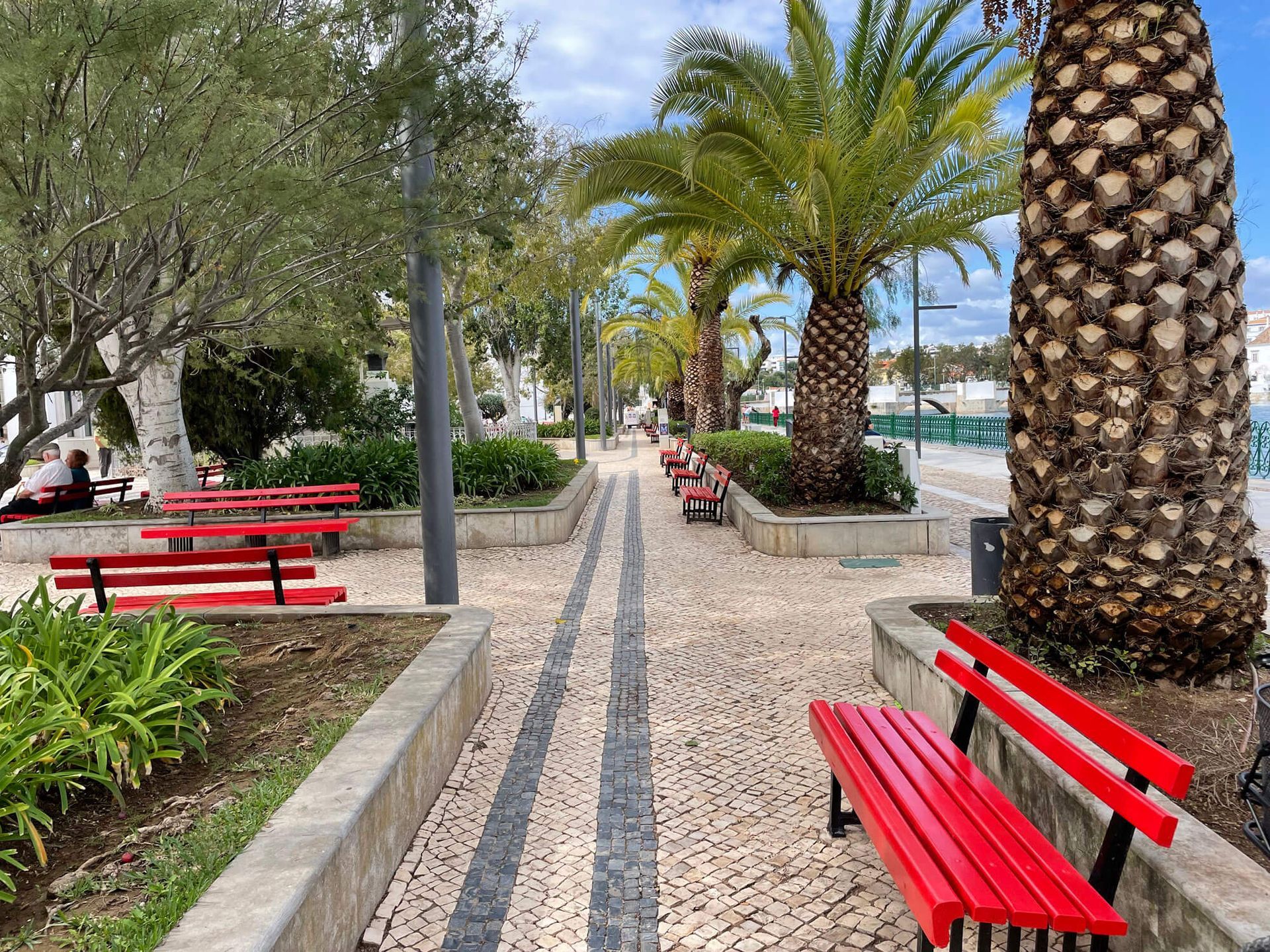 Algarve: ein Park mit roten Bänken und Palmen