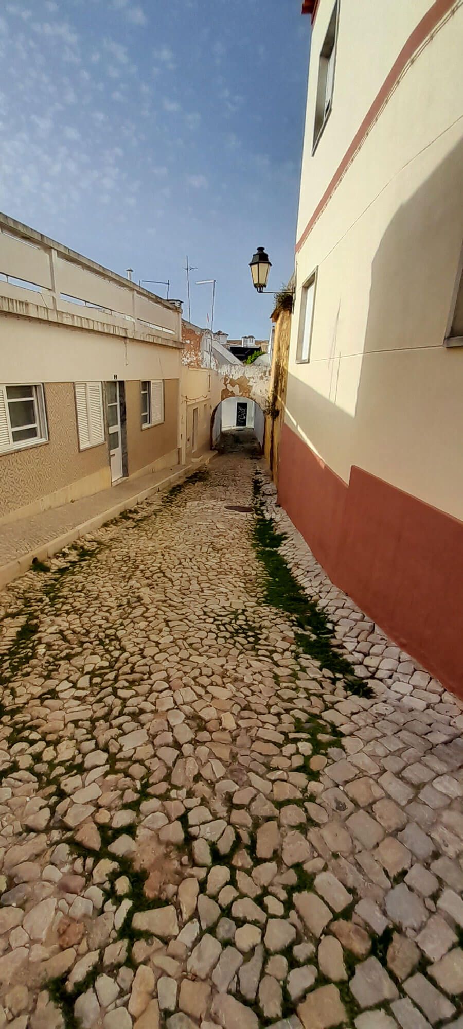 Kopfsteinpflasterstraße zwischen zwei Gebäuden an einem sonnigen Tag an der Algarve