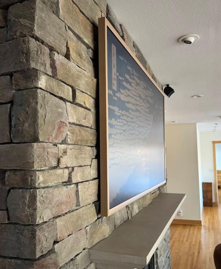 Interior hallway with stone wall, large framed artwork, bench, and hardwood floor