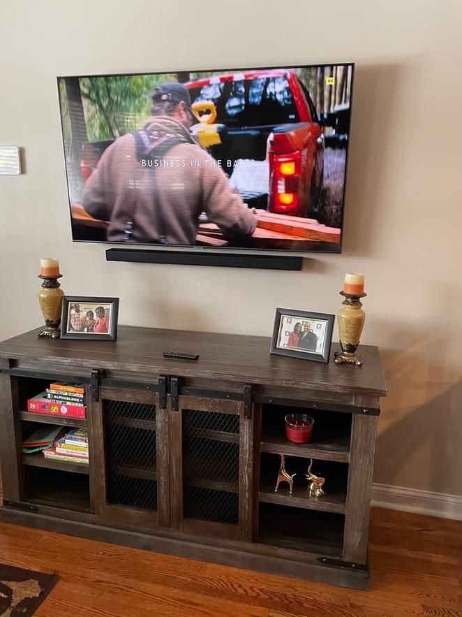 Living room TV showing a person near a red truck, with a dark wood media console below.