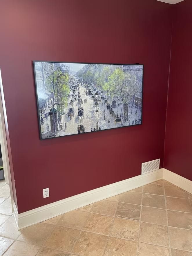 Framed city street artwork on a burgundy wall in a tiled room