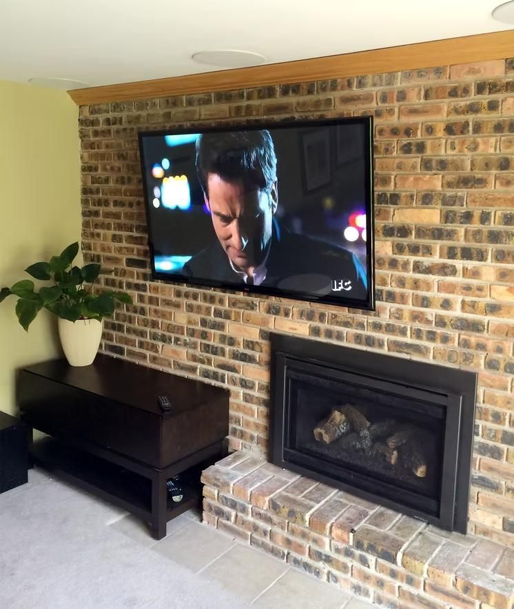 Living room with wall-mounted TV above a brick fireplace, dark wood bench, and potted plant