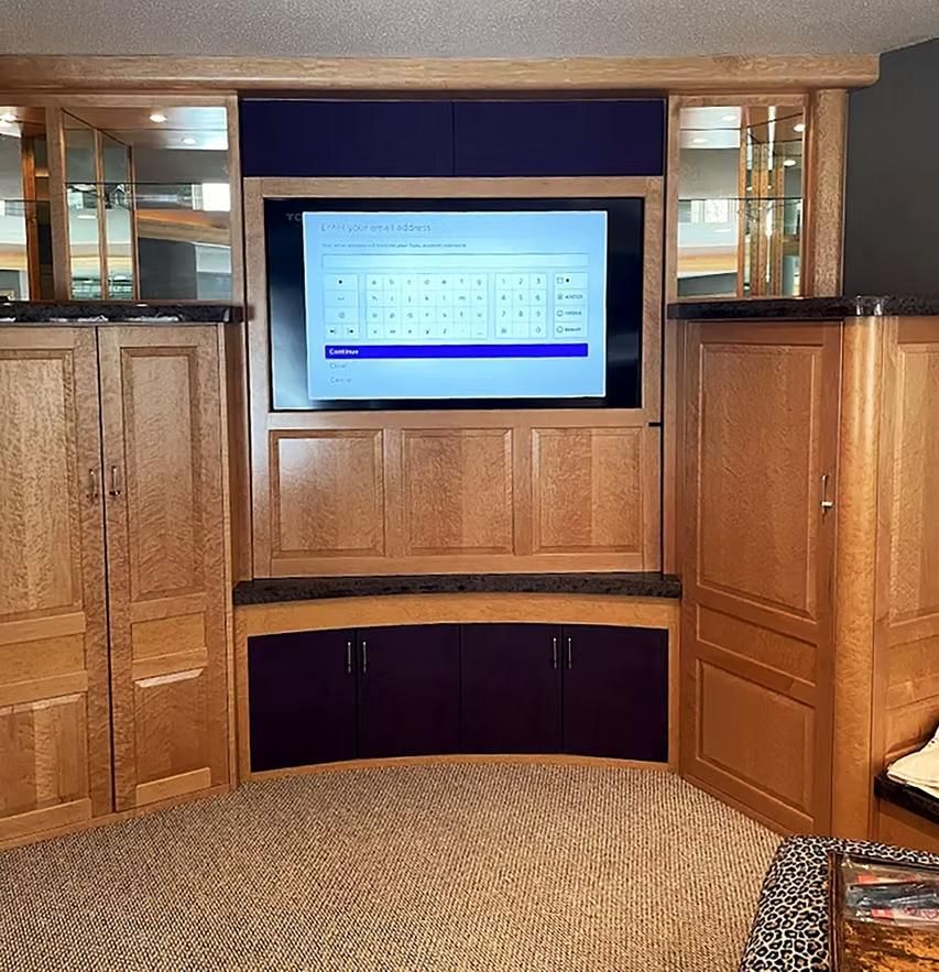 Wood-paneled living room with a wall-mounted TV and built-in cabinets around it