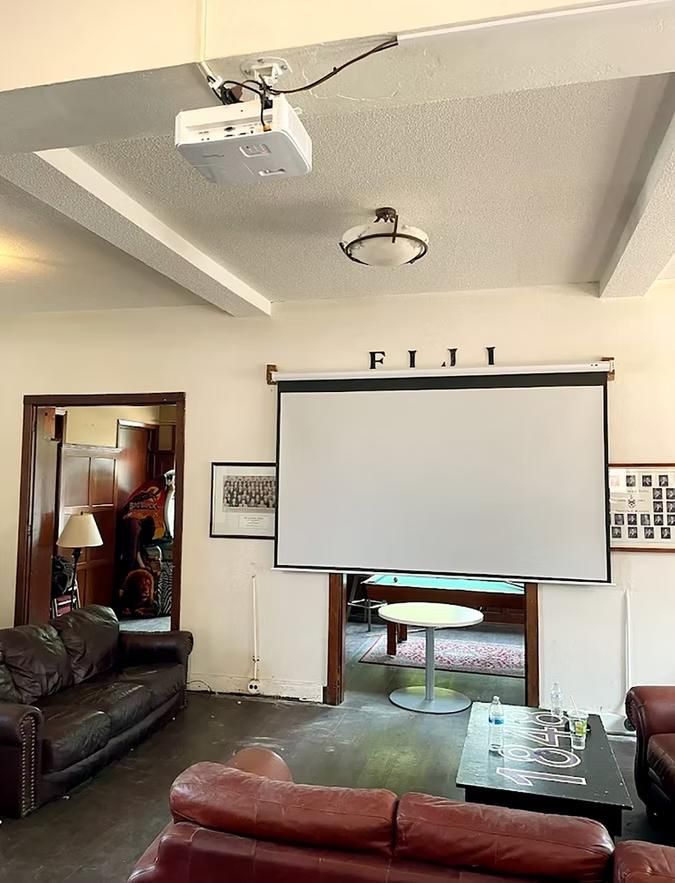 Living room with projector screen, leather sofas, coffee tables, and ceiling lights
