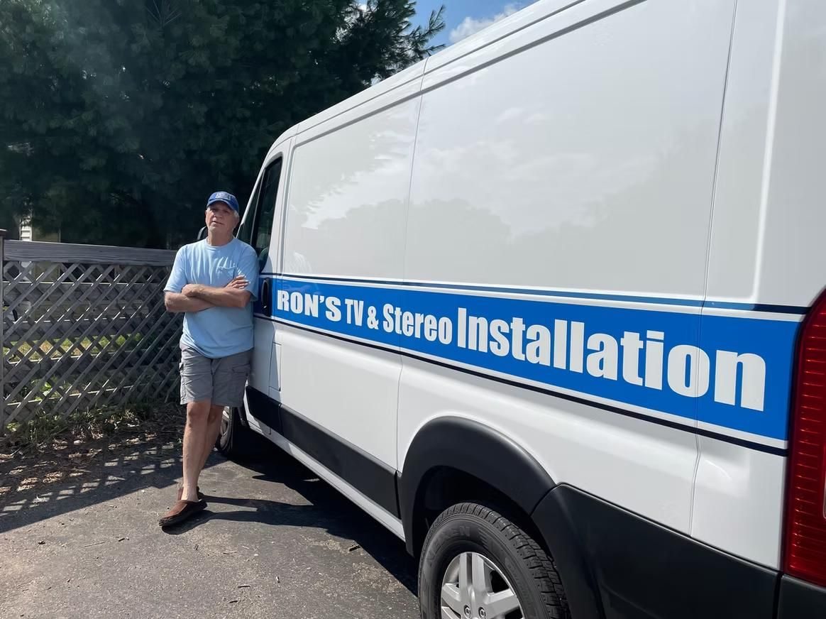 Man leaning against white installation van with blue stripe and text on the side