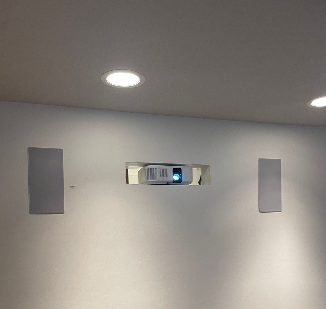 White wall-mounted speaker on a brown column beneath a tiled ceiling
