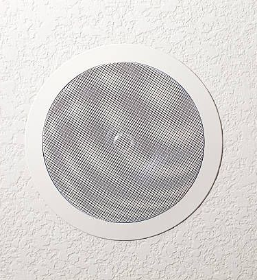 Close-up of three round speaker grilles in grayscale on a wall