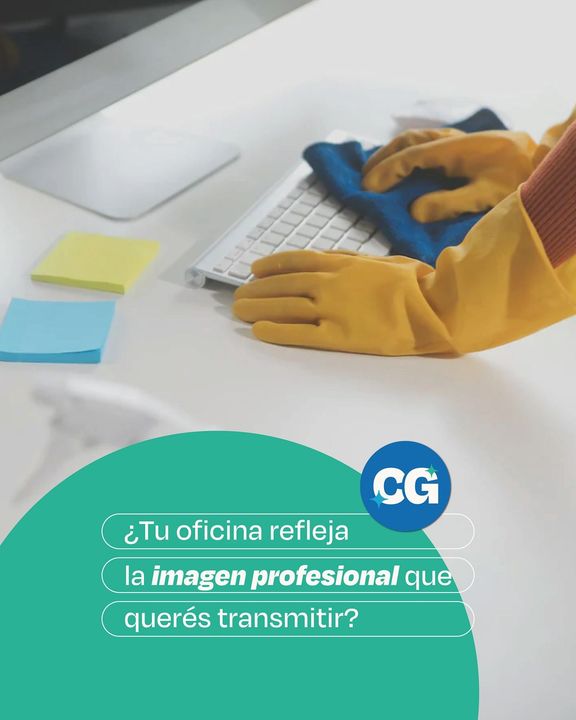 Persona con guantes amarillos limpiando un teclado blanco con un paño azul sobre un escritorio.