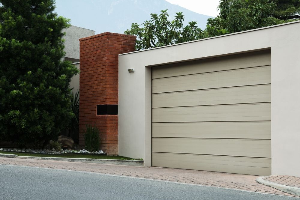 A white garage door is next to a brick building.