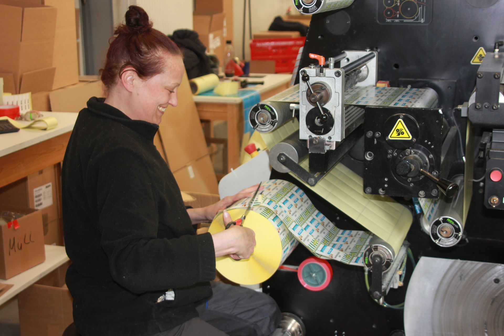 Person, die in einer Werkstatt Papier in eine große Druckmaschine einlegt
