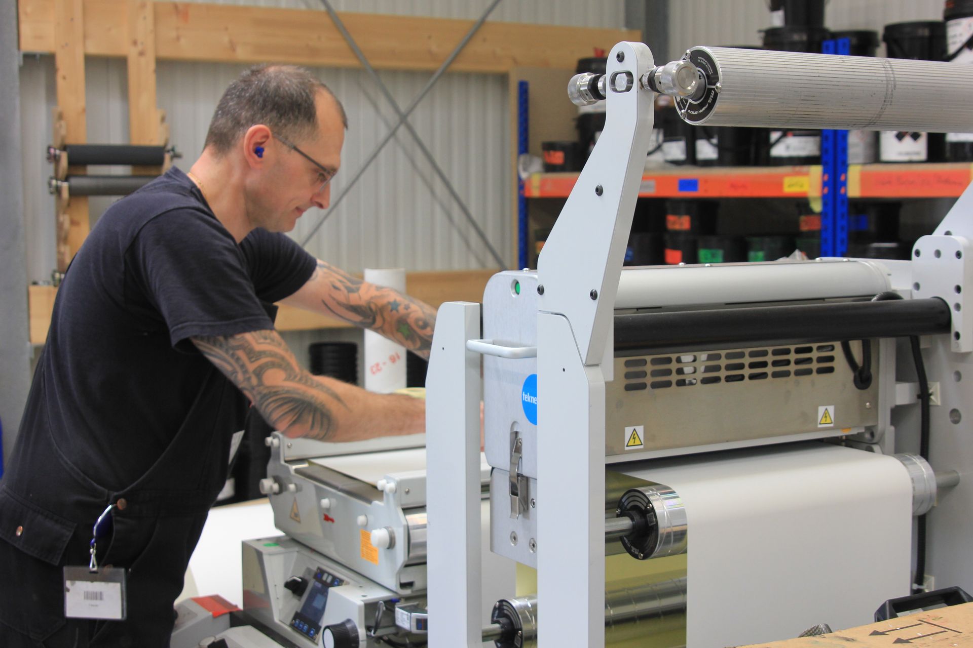 Mann bedient eine große industrielle Druckmaschine in einer Werkstatt