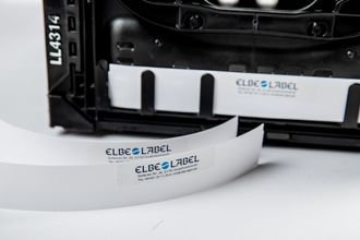 Nahaufnahme einer ELBE & LABEL Produktetikettenrolle in einer Maschine auf einer weißen Oberfläche