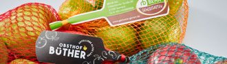 Netzbeutel mit buntem Obst, schwarzem „Bother“-Etikett und grünem Preisschild