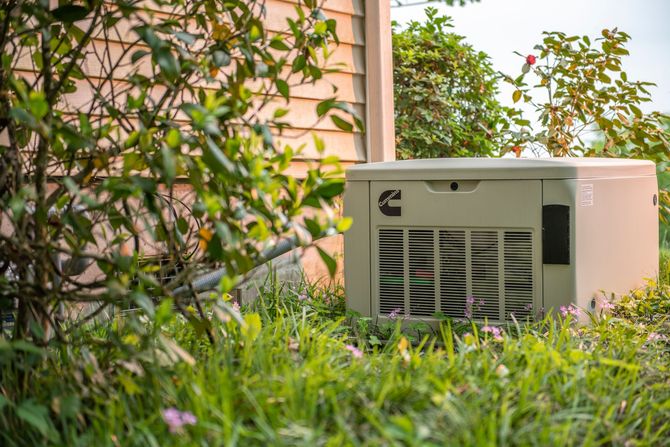 Outdoor HVAC unit beside a house, partly hidden by tall grass and shrubs