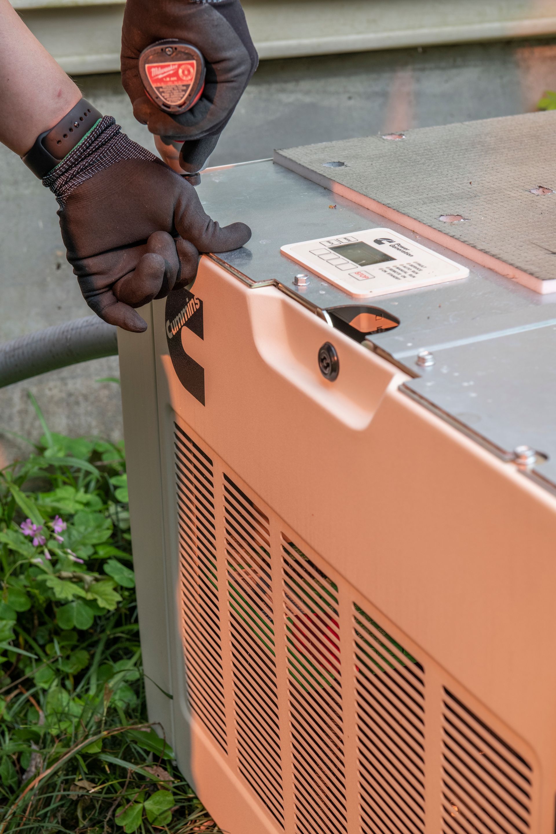 Gloved hands using a tool to service a beige outdoor HVAC unit next to a house
