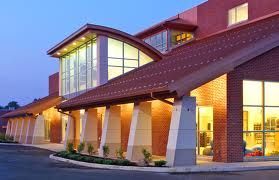 Brick building exterior at dusk with lit windows and a covered entrance