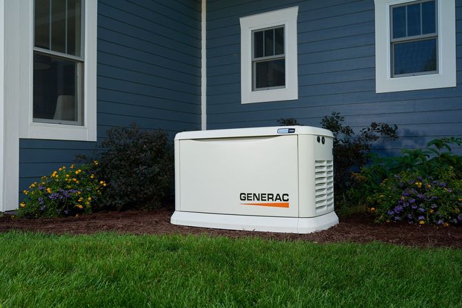White Generac standby generator beside a blue house on a grassy lawn