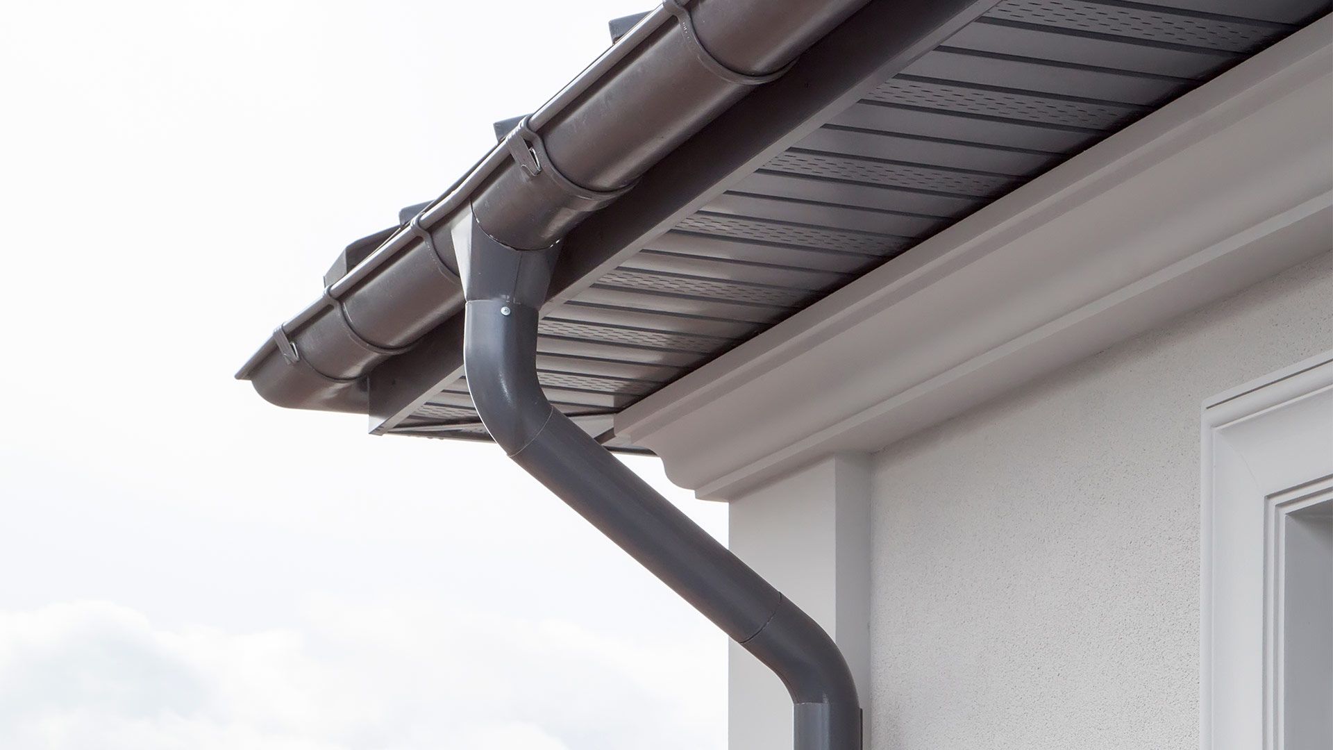 A close up of a gutter on the side of a house.