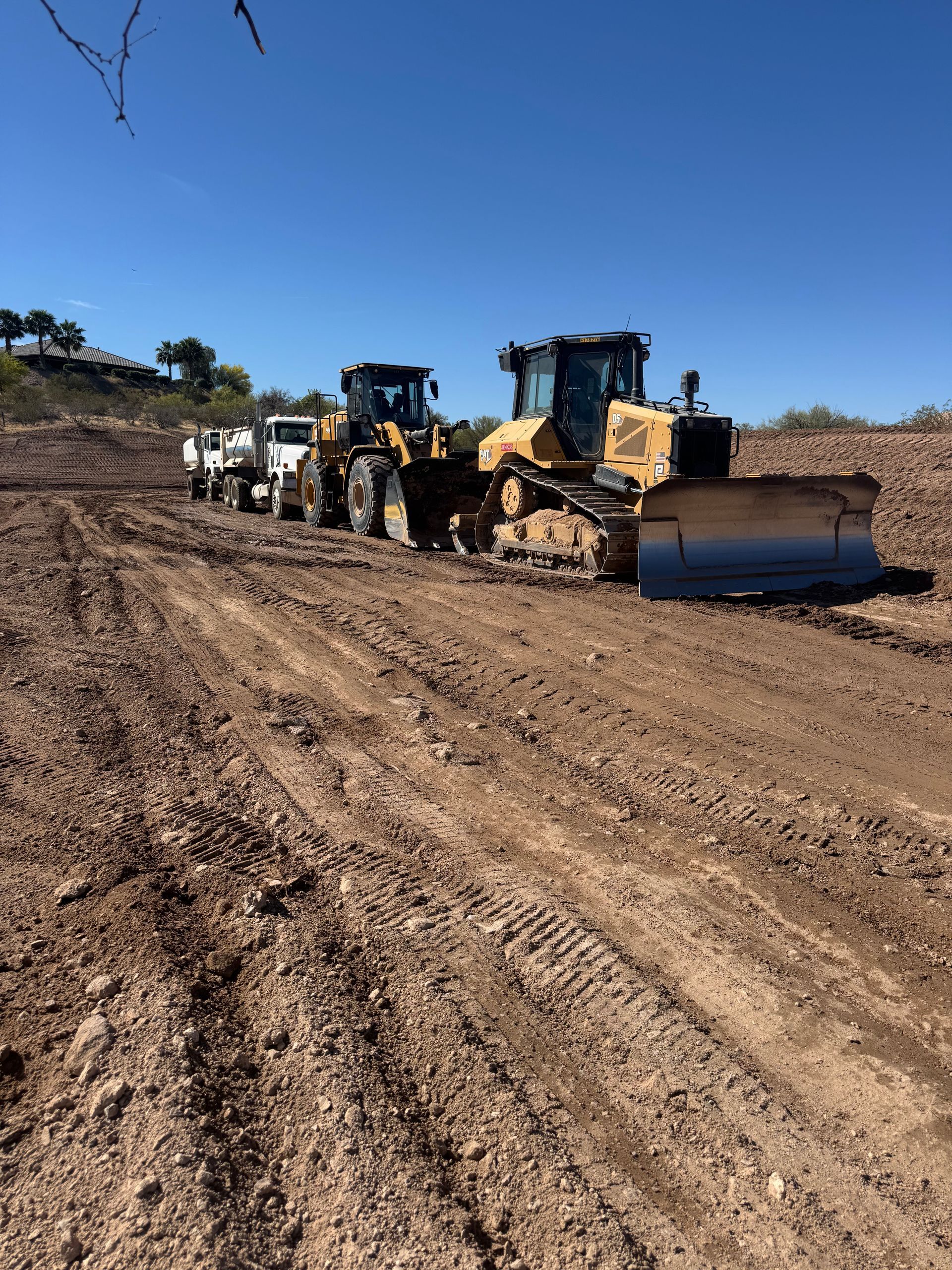 Bulldozers grading a dirt road on a sunny construction site