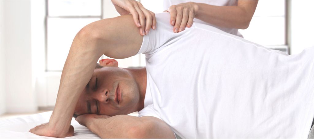 A woman is giving a man a massage on a bed.