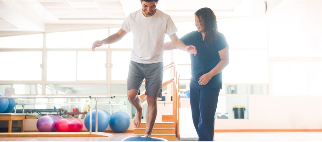 A man is doing exercises with a nurse in a gym.