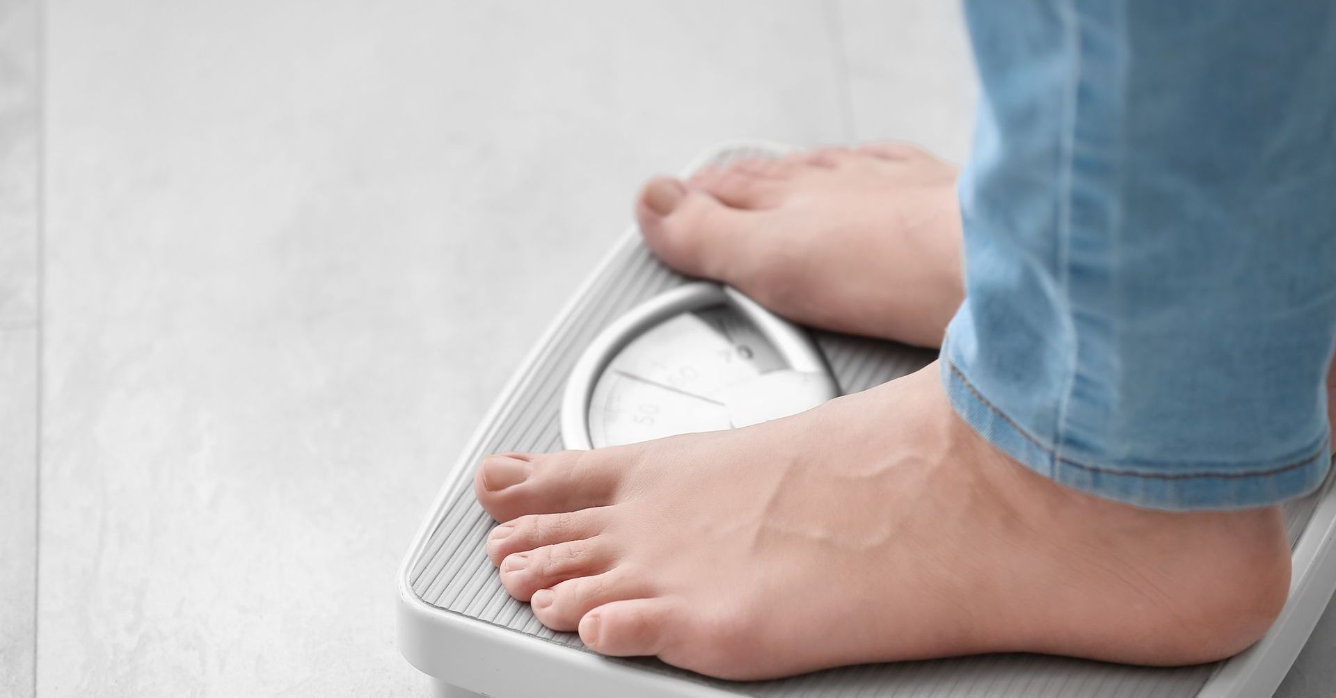 Person's bare feet standing on a gray scale; weight check.
