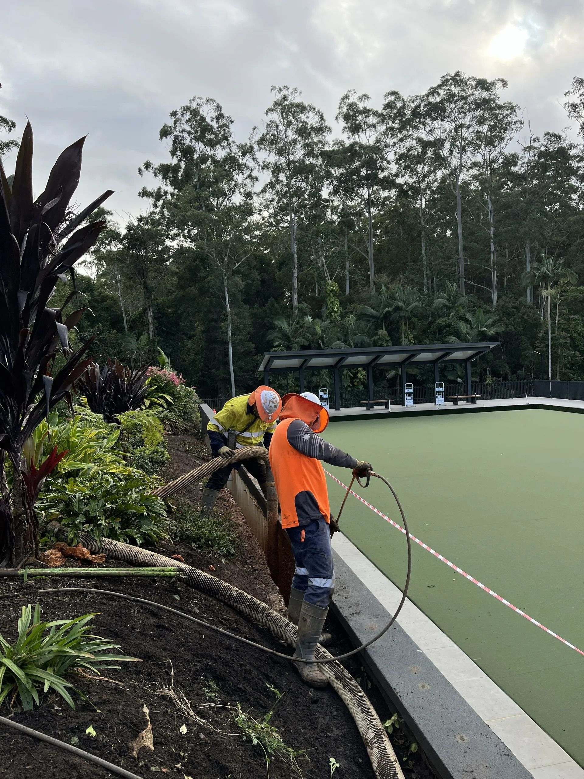 Two Workers in Orange Vests Near a Green Playing Field — Tyzac Group in Beerwah, QLD
