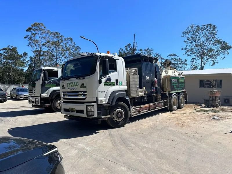 Two Large White and Green Trucks Parked Outside a Building on a Sunny Day — Tyzac Group in Beerwah, QLD