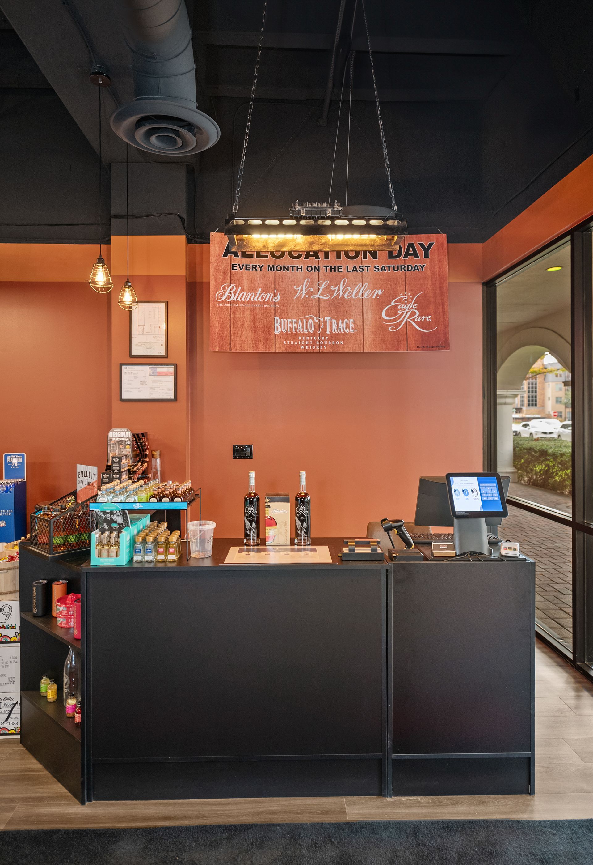 Cash register and display area in a shop with orange and black walls, sign that reads