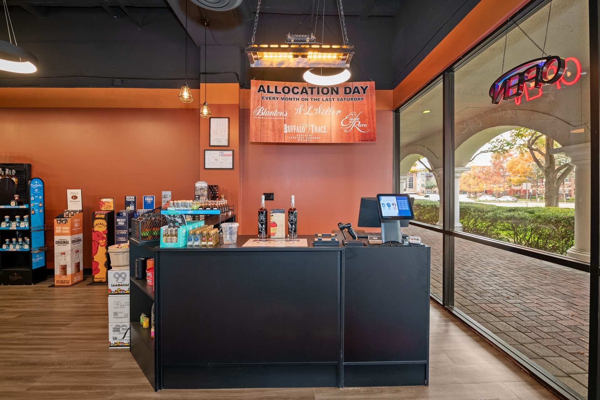 Liquor store interior with a black counter, orange walls, and large windows.