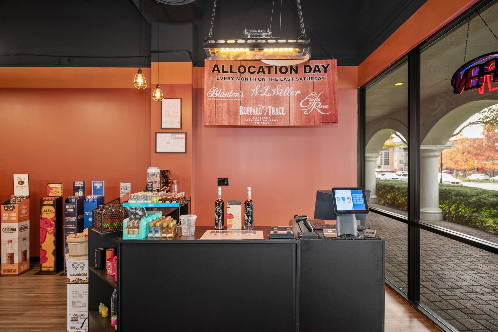 Inside of a store with a register, displaying a sign for Allocation Day; brick wall and shelves stocked with products.