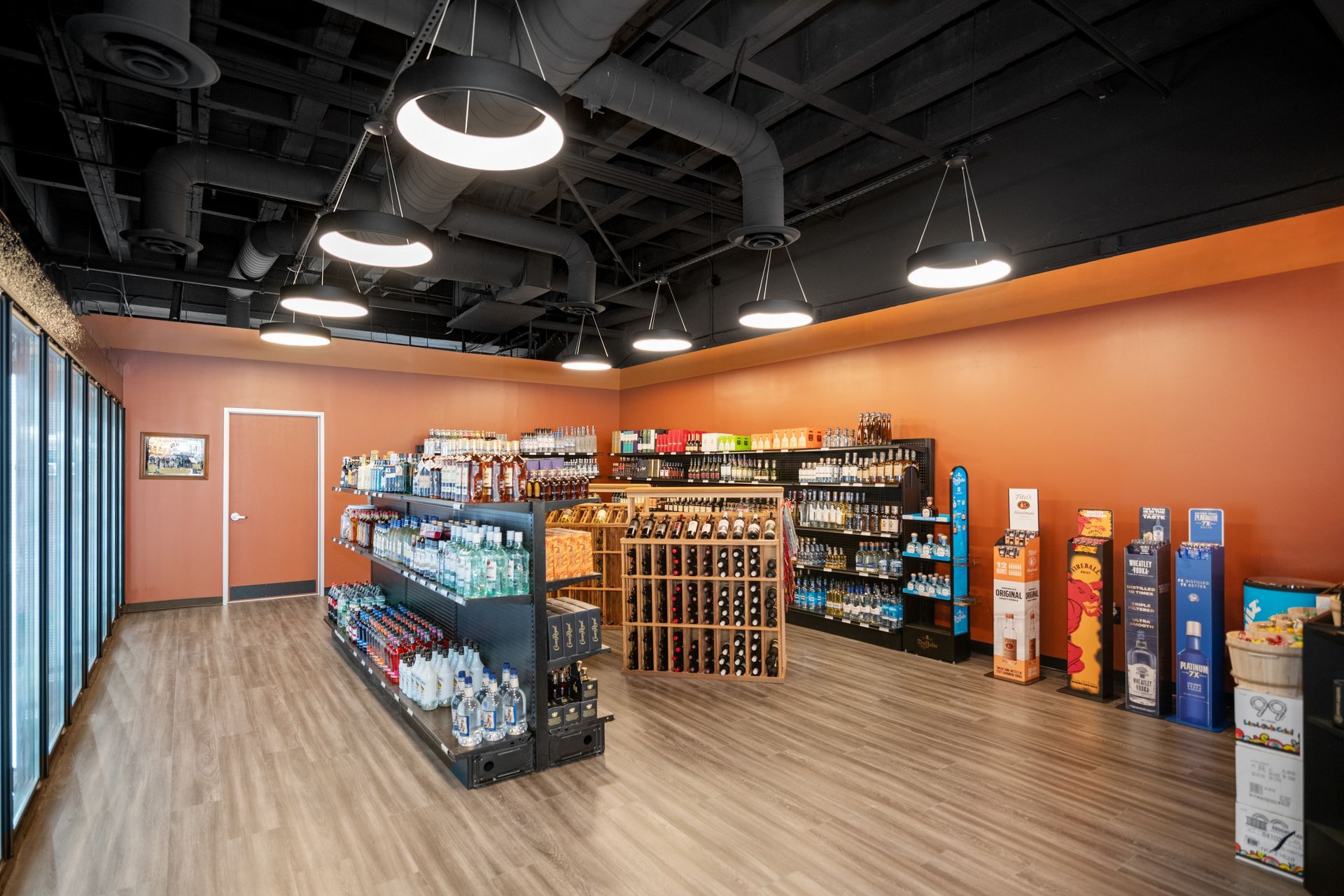 Interior of a small convenience store with shelves of products, wood floors, and orange walls.