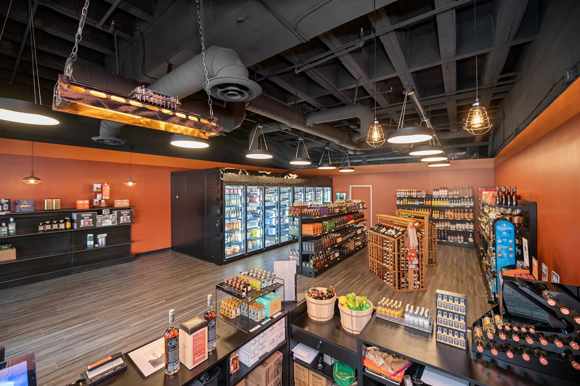 Interior of a liquor store with shelves of products, coolers, and checkout counter; orange walls.
