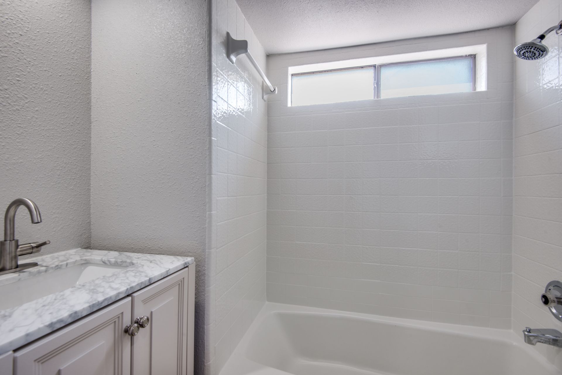 A bathroom remodel with a sink , tub , shower and window.